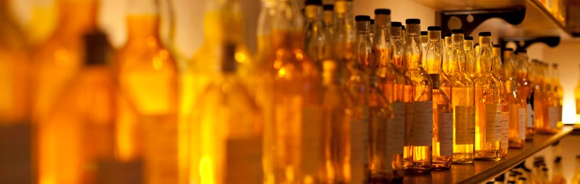 Whisky bottles on a shelf, lit in amber